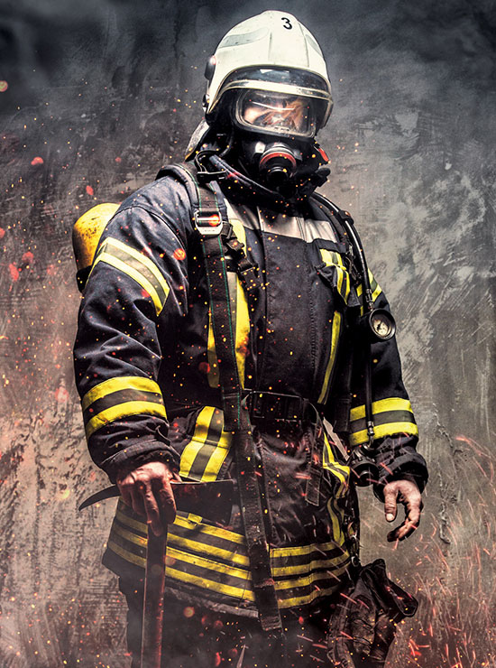 JUMBO-TEXTIL || Ihre Branche - PSA, Sicherheitssysteme, Elektro: Ein Feuerwehrmann in voller Schutzausrüstung inklusive Atemschutzmaske, umgeben von Rauch und Funken